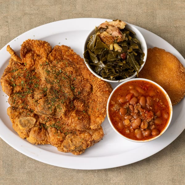 IDA MAE’S soul food plate with fried pork chop, collard greens, baked beans, and cornbread.