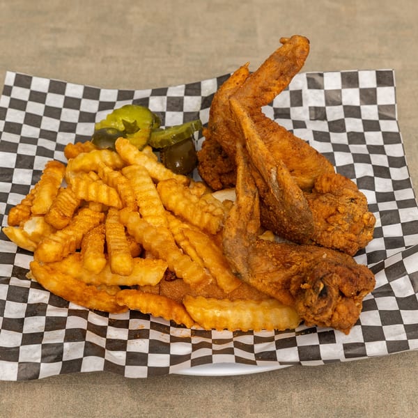IDA MAE’S fried chicken wings, crinkle-cut fries, and pickles on checkered paper.